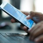 Businessman hand using laptop and mobile phone in office